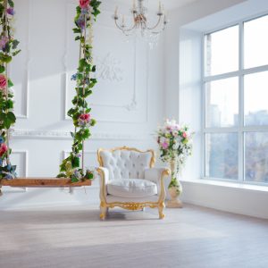 White leather vintage style chair in classical interior room with big window and flowers.