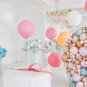 Boxes with flowers and a large pudrinitsa with balls and balloons in room decorated for birthday party