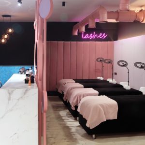 Interior of luxury stylish beauty salon.First plan pink armchairs and table for manicure and second plan place for eyelash extension .Pink concept design